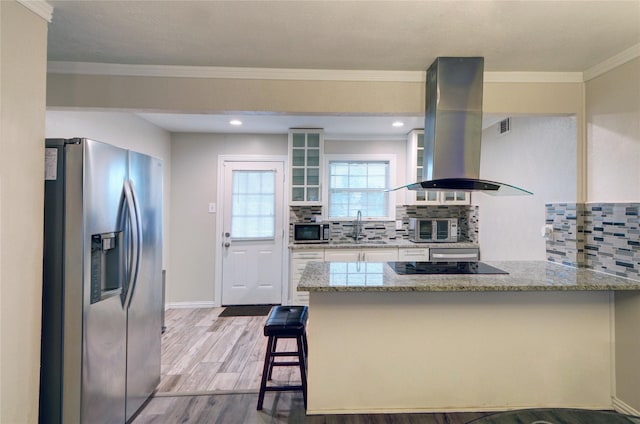 kitchen featuring appliances with stainless steel finishes, light wood-style floors, a sink, island range hood, and light stone countertops