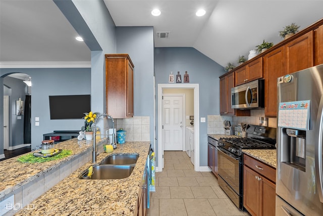 kitchen featuring stainless steel appliances, light stone countertops, sink, and separate washer and dryer