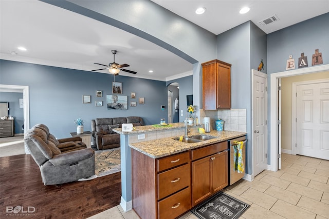 kitchen with sink, light stone counters, dishwasher, kitchen peninsula, and backsplash