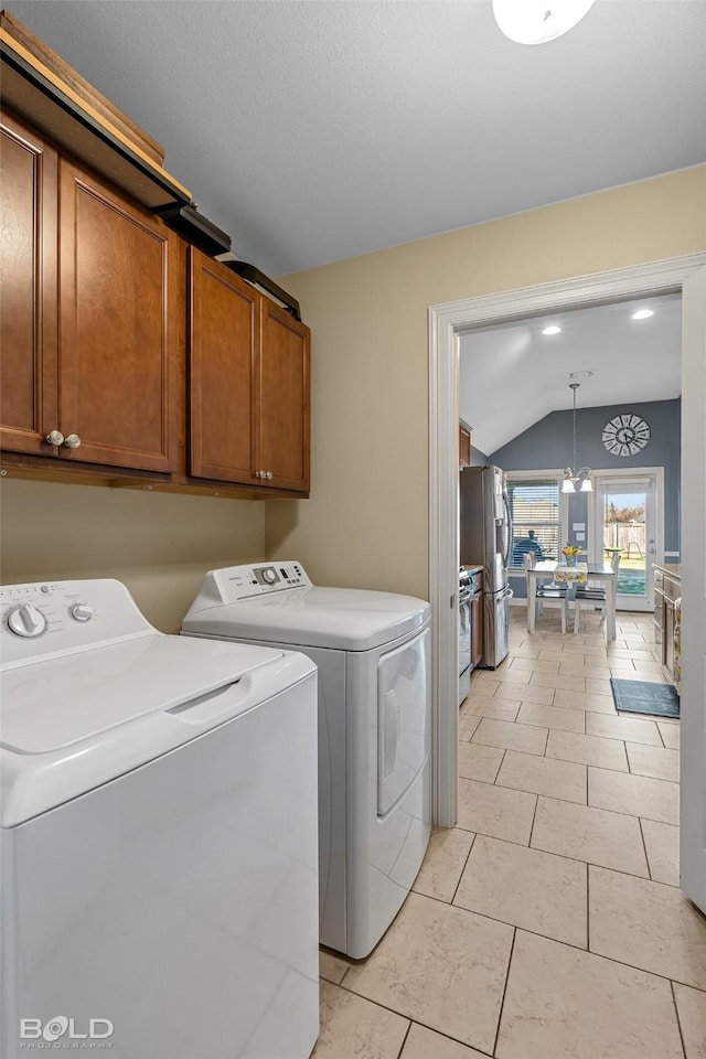 washroom with a notable chandelier, light tile patterned floors, washer and clothes dryer, and cabinets