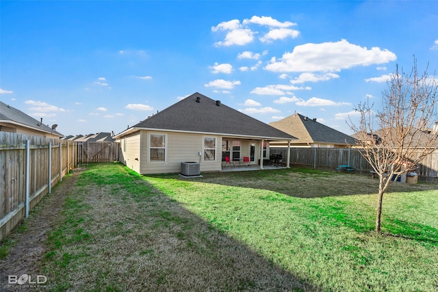 rear view of house with a patio, a yard, and central AC