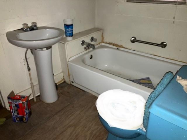 bathroom featuring wood-type flooring, toilet, and a bathing tub