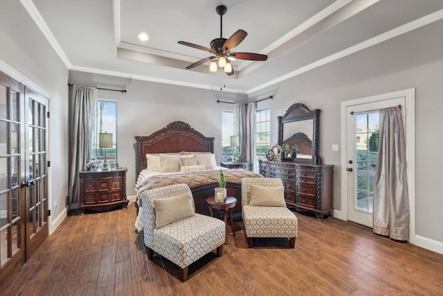 bedroom with multiple windows, access to exterior, hardwood / wood-style flooring, and a raised ceiling