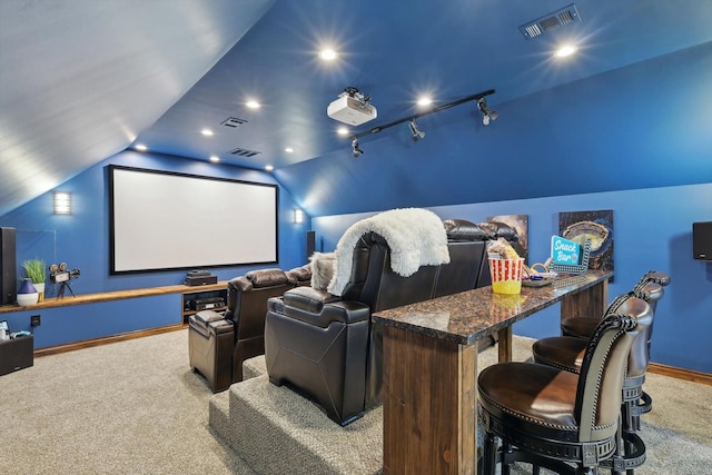 carpeted cinema featuring vaulted ceiling and track lighting