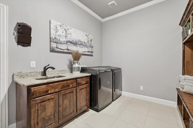 clothes washing area with sink, light tile patterned floors, cabinets, ornamental molding, and washer and dryer