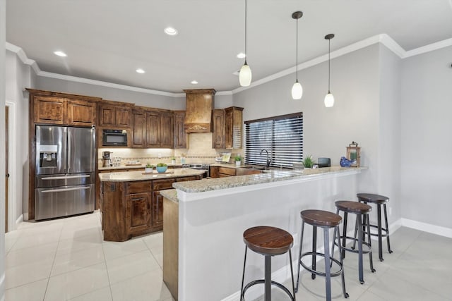 kitchen featuring hanging light fixtures, kitchen peninsula, stainless steel appliances, light stone countertops, and custom range hood