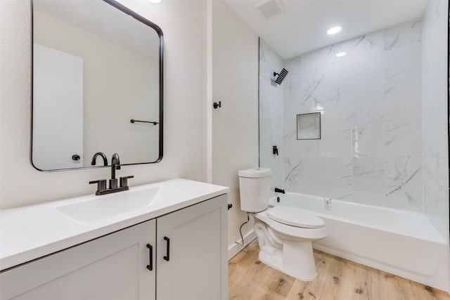 full bathroom featuring tiled shower / bath, vanity, toilet, and hardwood / wood-style floors