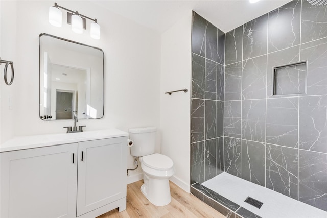 bathroom with vanity, hardwood / wood-style floors, toilet, and tiled shower