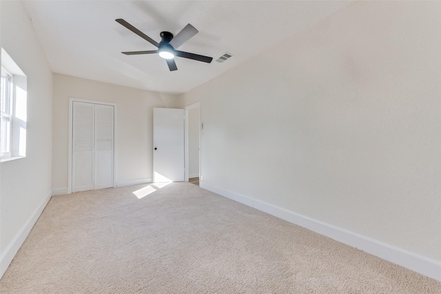 unfurnished bedroom with light colored carpet, ceiling fan, and a closet