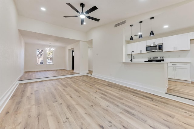 unfurnished living room with ceiling fan with notable chandelier and light hardwood / wood-style floors