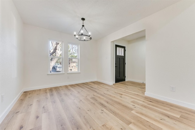 unfurnished dining area with an inviting chandelier and light hardwood / wood-style floors