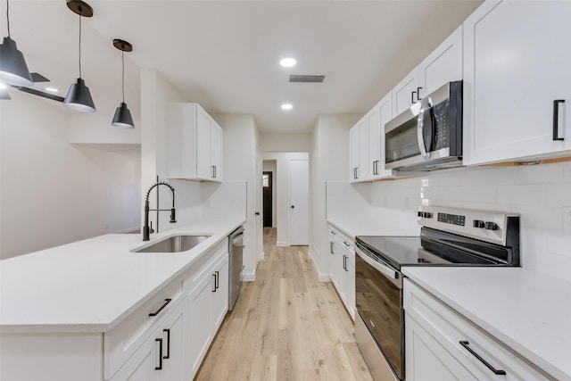 kitchen with white cabinetry, appliances with stainless steel finishes, sink, and pendant lighting