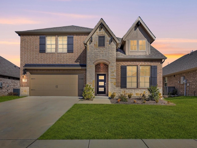 view of front of property featuring stone siding, brick siding, driveway, and a lawn