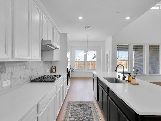 kitchen featuring sink, white cabinetry, pendant lighting, stainless steel appliances, and a kitchen island with sink