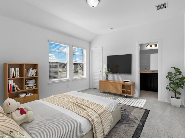 carpeted bedroom featuring lofted ceiling and ensuite bathroom