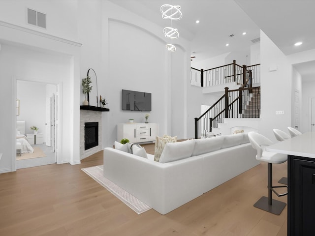 living room with a high ceiling, a chandelier, and light hardwood / wood-style flooring