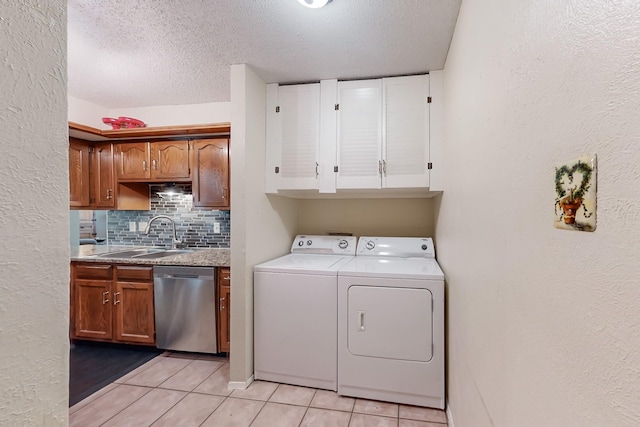 laundry room featuring sink, light tile patterned floors, a textured ceiling, and independent washer and dryer