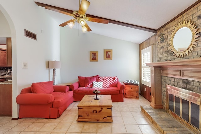 living room featuring a brick fireplace, light tile patterned floors, lofted ceiling with beams, and ceiling fan