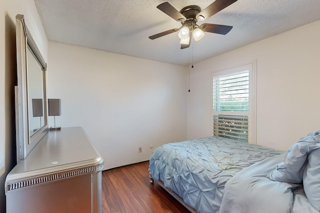 bedroom with ceiling fan, a textured ceiling, and dark hardwood / wood-style flooring