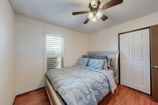 bedroom with a textured ceiling, dark wood-type flooring, a closet, and ceiling fan