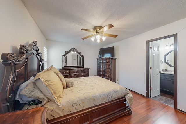 bedroom with ceiling fan, dark wood-type flooring, a textured ceiling, and ensuite bath