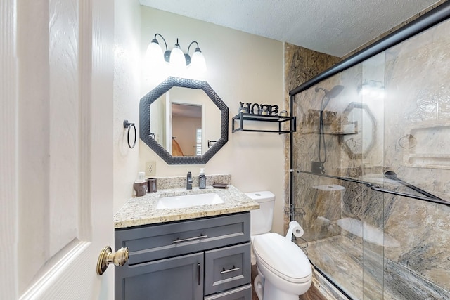 bathroom featuring vanity, toilet, a shower with shower door, and a textured ceiling