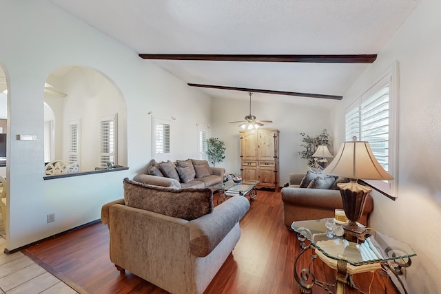 living room with wood-type flooring, lofted ceiling with beams, and ceiling fan