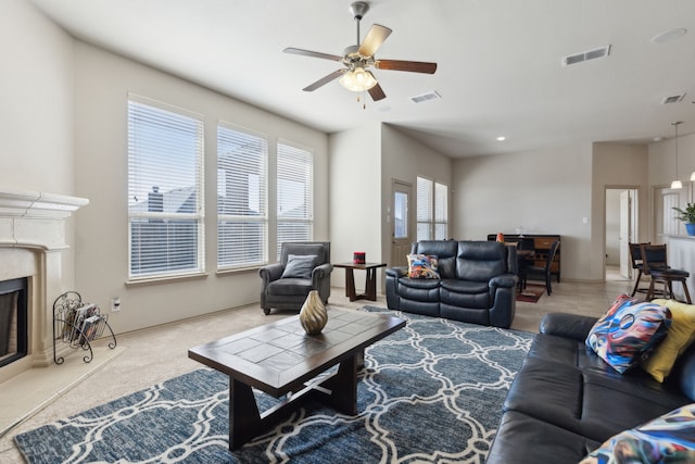 living room with a high end fireplace and ceiling fan