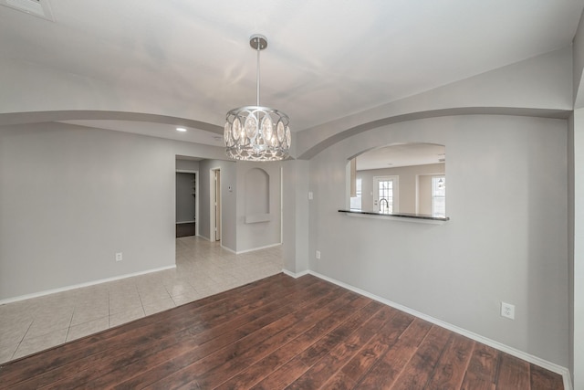 spare room with an inviting chandelier and wood-type flooring