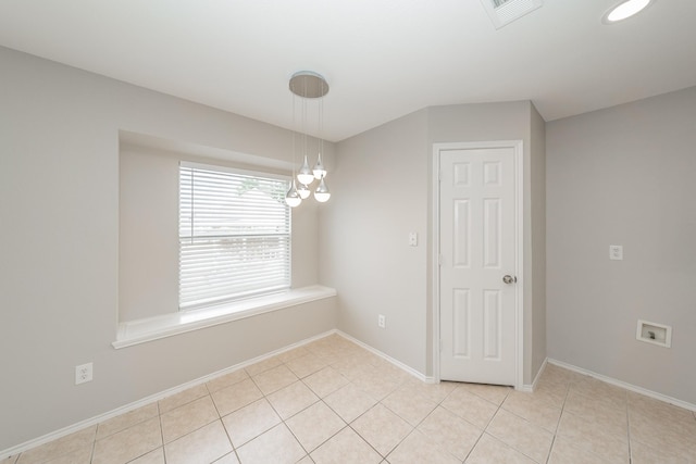 tiled spare room with a notable chandelier