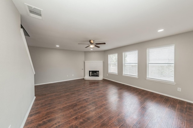 unfurnished living room featuring ceiling fan, dark hardwood / wood-style floors, and a fireplace