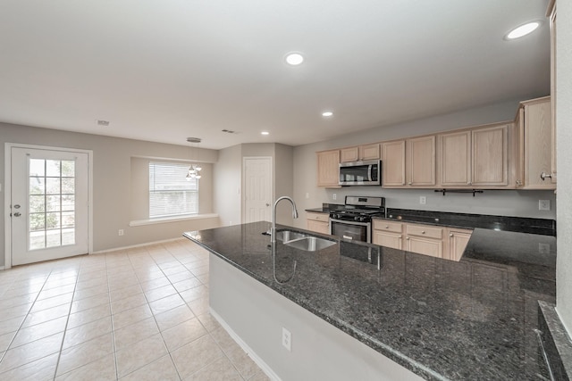 kitchen with sink, light tile patterned floors, light brown cabinets, dark stone counters, and stainless steel appliances