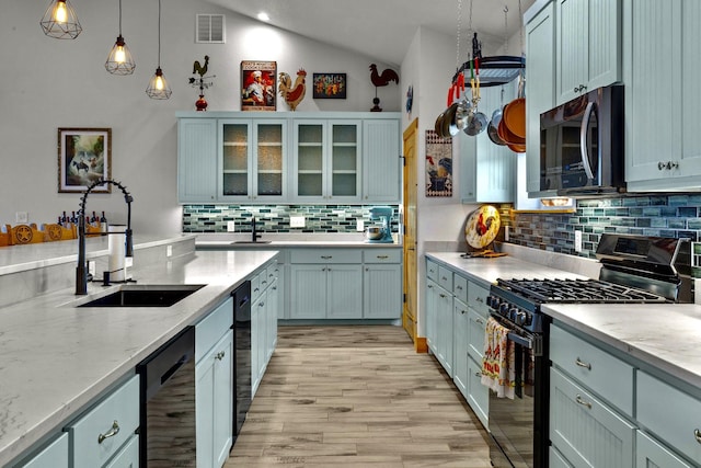 kitchen featuring pendant lighting, lofted ceiling, sink, light hardwood / wood-style floors, and black appliances