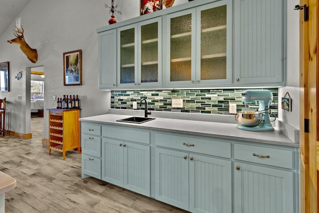 kitchen with tasteful backsplash, sink, and light wood-type flooring