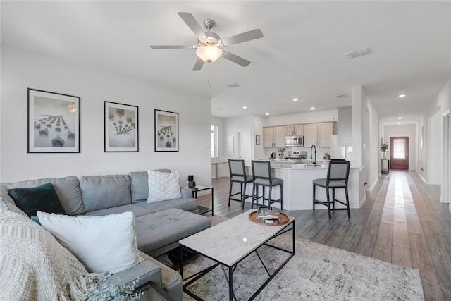 living room featuring sink, hardwood / wood-style flooring, and ceiling fan