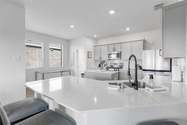 kitchen featuring appliances with stainless steel finishes, kitchen peninsula, a kitchen island, and gray cabinetry