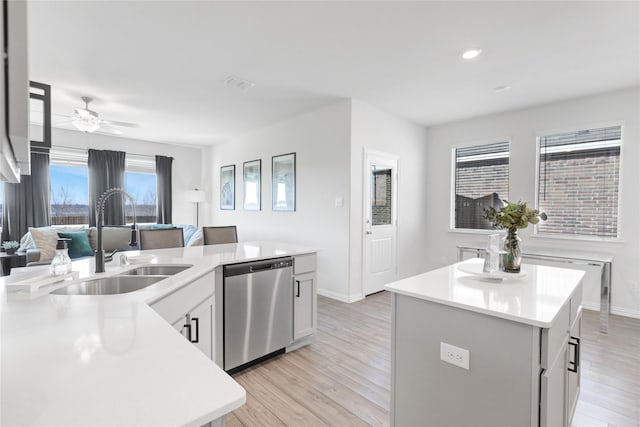 kitchen with sink, light hardwood / wood-style flooring, stainless steel dishwasher, and an island with sink