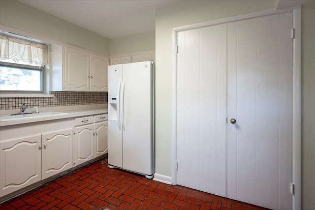 kitchen featuring white cabinetry, sink, decorative backsplash, and white fridge with ice dispenser