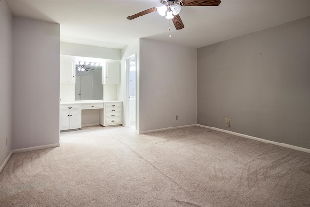 unfurnished bedroom featuring ceiling fan, light colored carpet, and built in desk