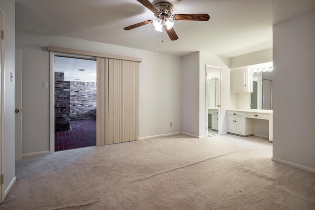 unfurnished bedroom featuring ensuite bathroom, light colored carpet, ceiling fan, and built in desk