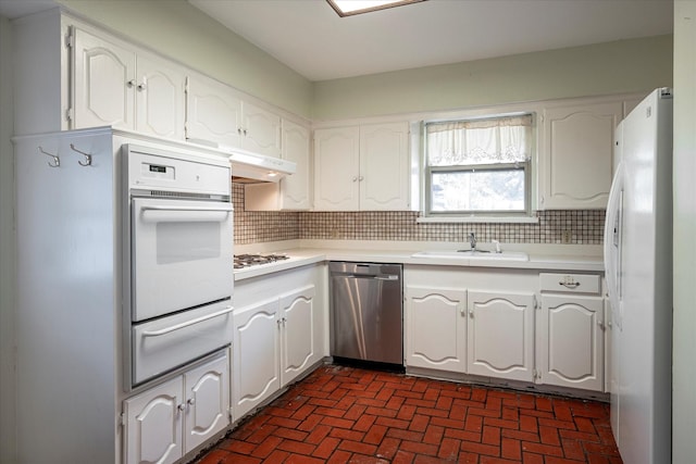 kitchen with white cabinetry, white appliances, sink, and decorative backsplash