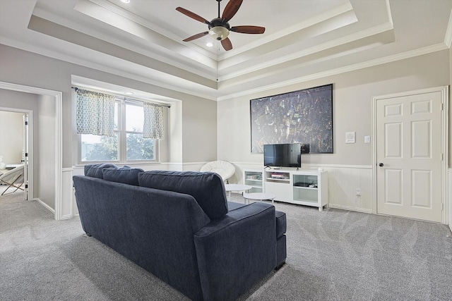 carpeted living room with ceiling fan, ornamental molding, and a tray ceiling