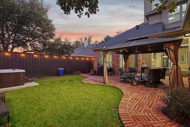 yard at dusk featuring a gazebo, a hot tub, and a patio