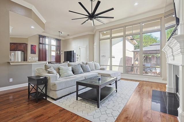 living room with ceiling fan, ornamental molding, sink, and hardwood / wood-style floors