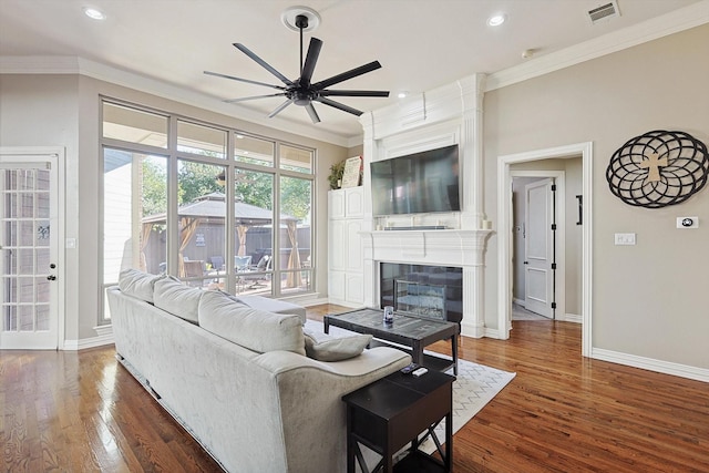 living room with a fireplace, ornamental molding, dark hardwood / wood-style floors, and ceiling fan