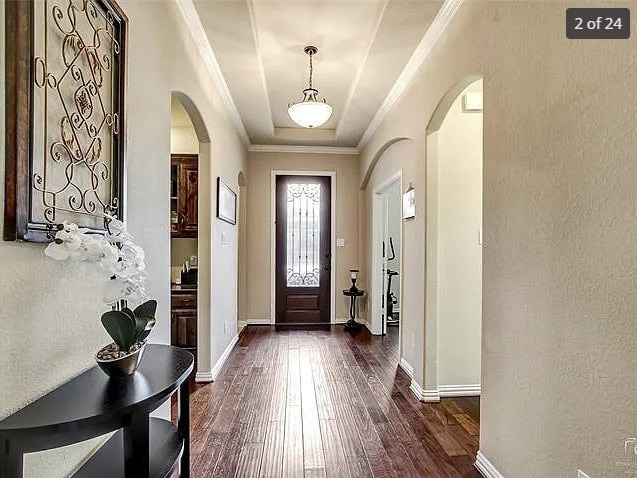 entrance foyer featuring crown molding and dark hardwood / wood-style flooring