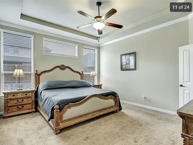 carpeted bedroom featuring ornamental molding, ceiling fan, and a tray ceiling