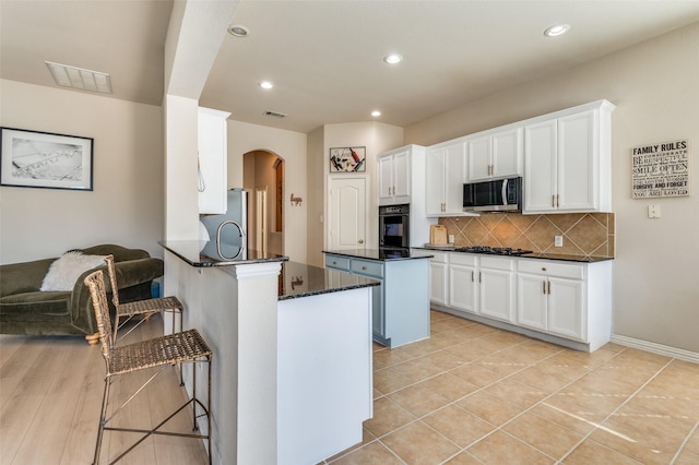 kitchen with backsplash, stainless steel appliances, kitchen peninsula, and white cabinets