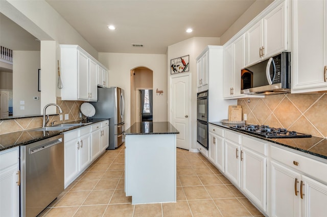 kitchen with sink, dark stone countertops, white cabinetry, black appliances, and a kitchen island