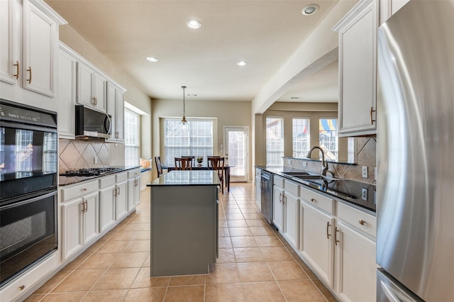 kitchen featuring sink, decorative light fixtures, a kitchen island, stainless steel appliances, and white cabinets